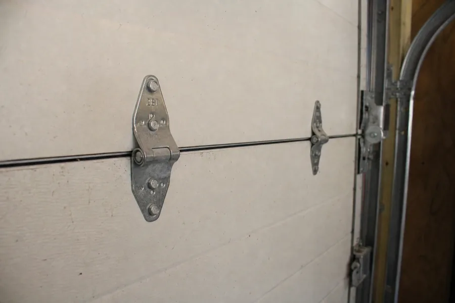 Hinges and roller along a panel seam of a garage door in Wichita, KS
