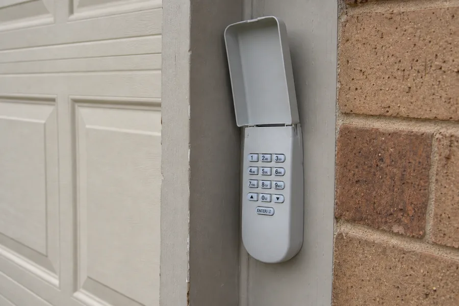 Keypad on the frame of a two-car garage door on a brick house